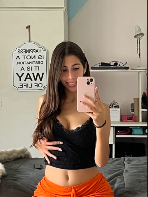 Selena Bloom trägt ein sexy schwarzes Top und orangefarbene Shorts.